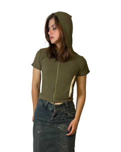 Person wearing a green top and dark denim overalls standing on a white floor with a wooden floor visible.